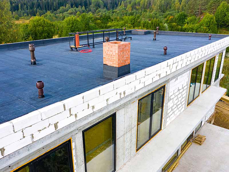 Side view of a commercial building being constructed with a flat, black roof