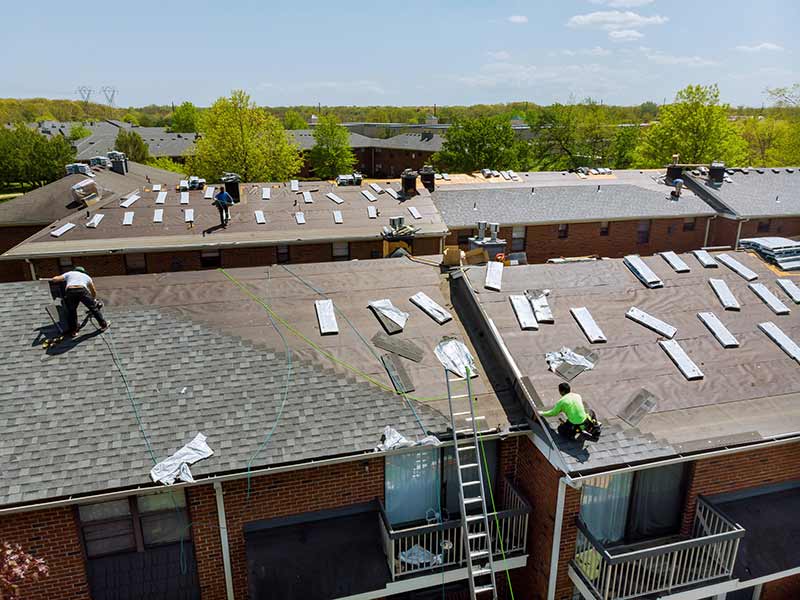 ECI: Roofing Tuckpointing Stone Gutters Co. workers installing new shingles on apartment buildings